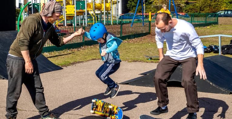 Young children skateboarding with older male and female