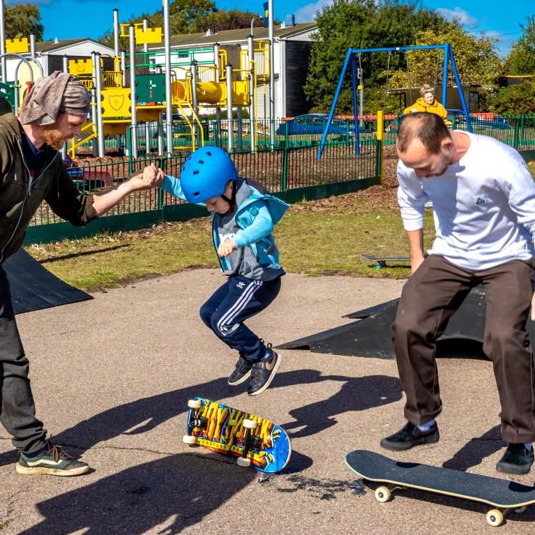 Young children skateboarding with older male and female