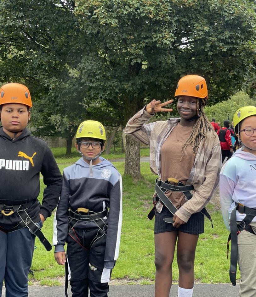 Children stood in a line wear protect gear needed for a ropes course 